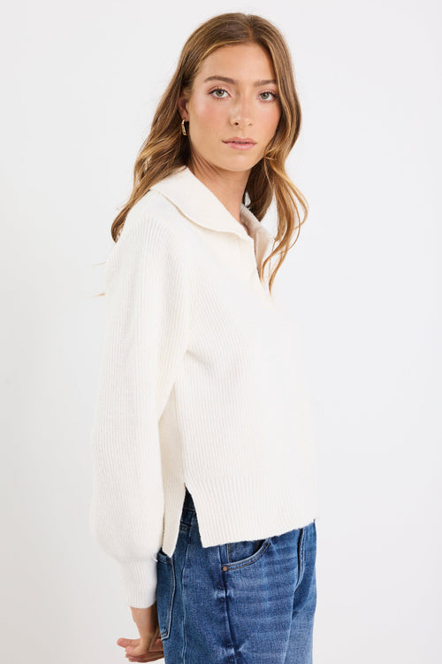 Woman wearing a white sweater and blue jeans against a white background