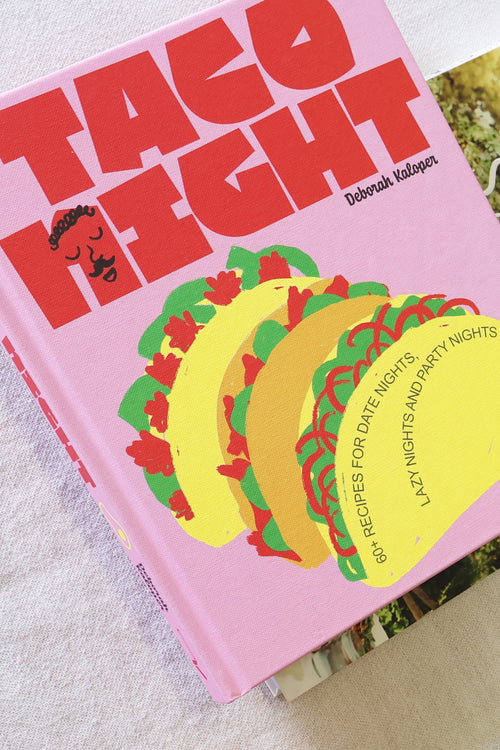 Tabletop scene with a book, grapes, fruit, and decorative items on a light surface.