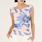 Woman wearing a sleeveless top with blue floral pattern on a white background