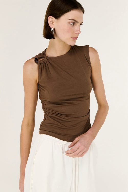Woman wearing a brown sleeveless top with a knot detail on a white background