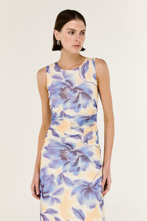 Woman wearing a sleeveless dress with blue floral pattern on a plain background