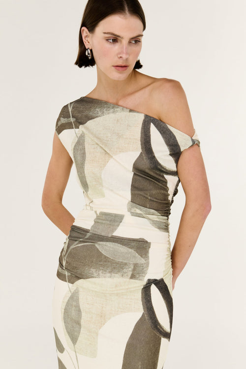 Woman wearing a one-shoulder dress with abstract pattern on a plain background