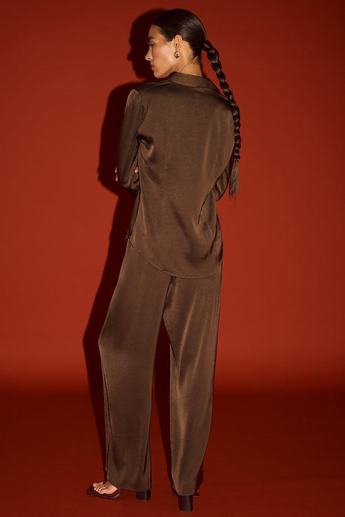 Person wearing a brown outfit against a red background