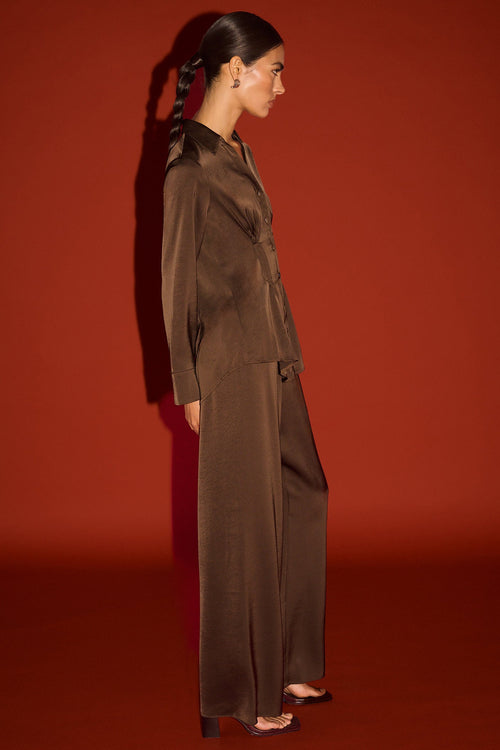 Woman in a brown outfit standing against a red background