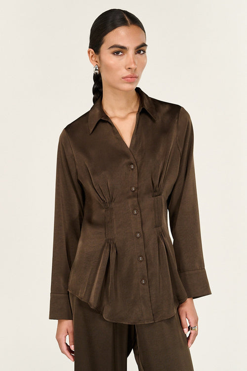 Woman wearing a brown blouse with a peplum waist on a white background