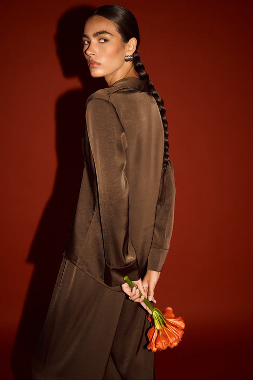 Woman in a brown outfit holding orange flowers against a red background