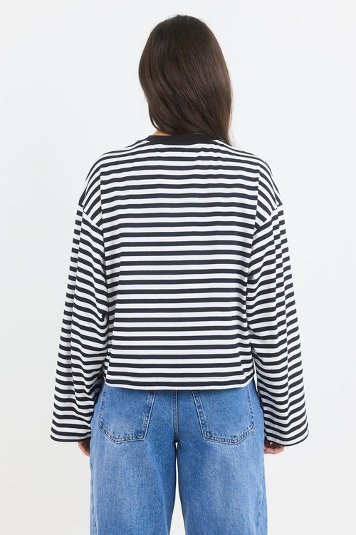 Person wearing a black and white striped shirt and blue jeans on a white background
