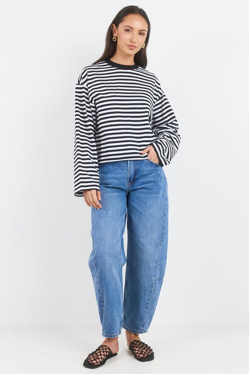 Woman wearing a striped sweater and blue jeans on a white background