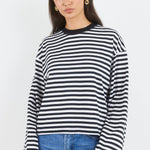 Woman wearing a black and white striped sweater and blue jeans on a white background