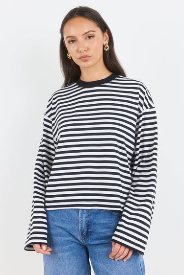 Woman wearing a black and white striped sweater and blue jeans on a white background