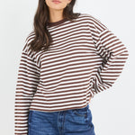 Woman wearing a striped long-sleeve shirt and blue jeans on a white background