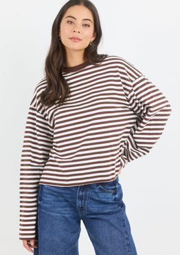Woman wearing a striped long-sleeve shirt and blue jeans on a white background
