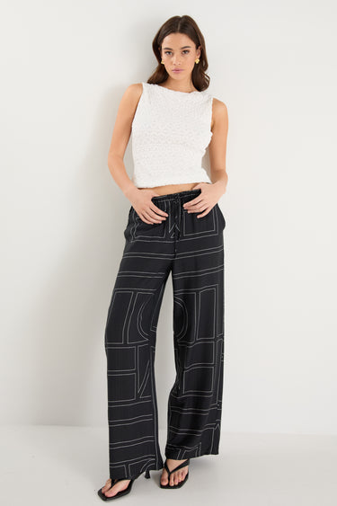 model wears a black wide leg pant with a white tank top