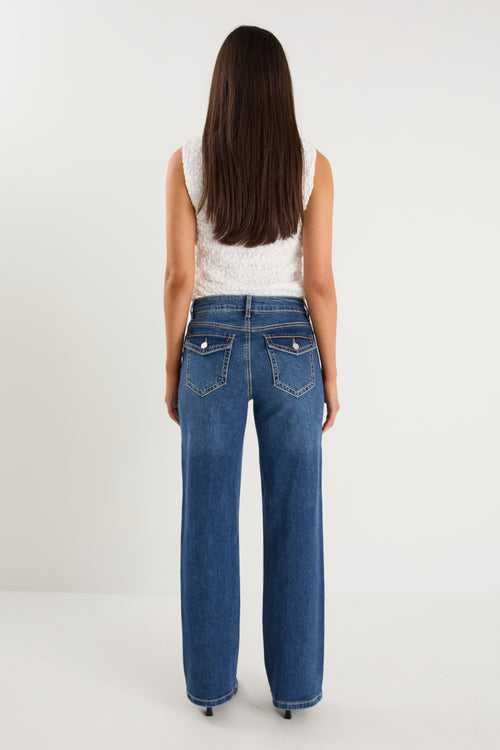 model wears a pair of blue jeans with a white tank top