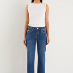 model wears a pair of blue jeans with a white tank top