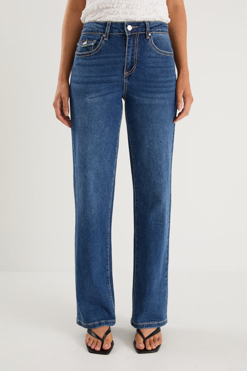 model wears a pair of blue jeans with a white tank top