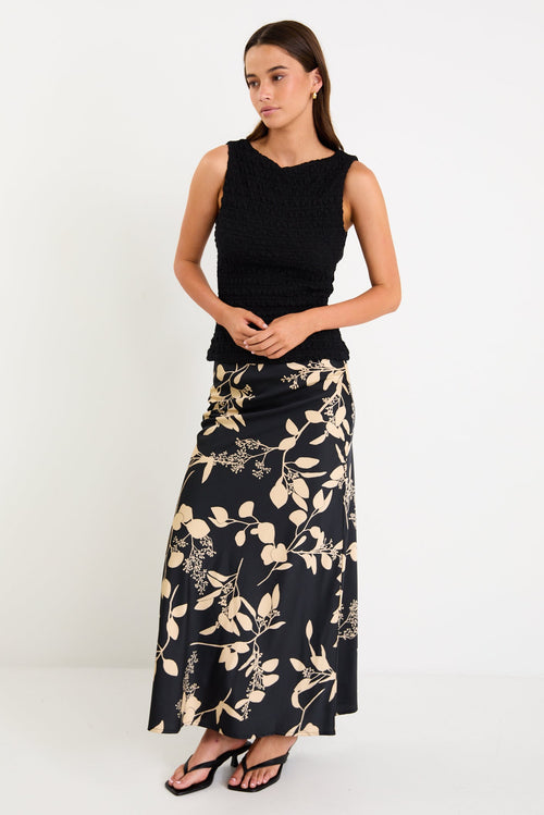 Model wearing a black and beige floral satin bias-cut maxi skirt styled with a black top.