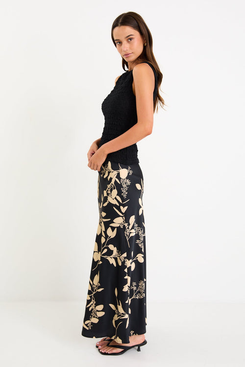 Model wearing a black and beige floral satin bias-cut maxi skirt styled with a black top.