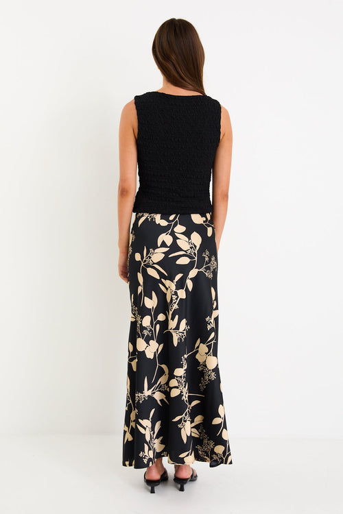 Model wearing a black and beige floral satin bias-cut maxi skirt styled with a black top.
