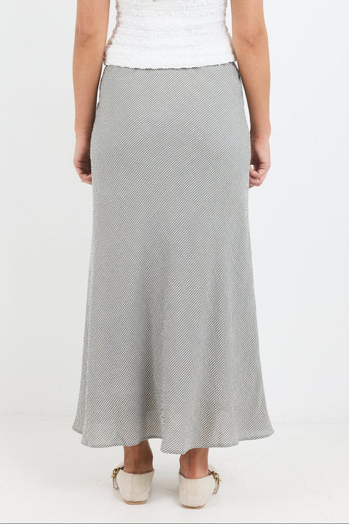 Woman wearing a white sleeveless top and gray skirt on a white background