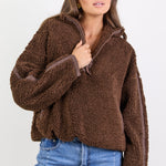 Woman wearing a brown fleece jacket and blue jeans on a white background