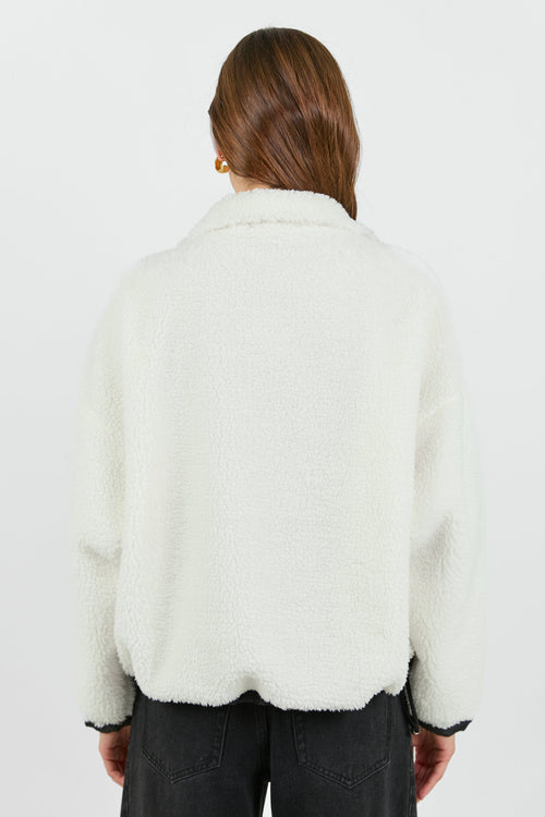 This cozy cream fleece jacket features a zip-up front, sporty black side stripes, and a relaxed fit, paired with black wash jeans for a casual yet stylish look.