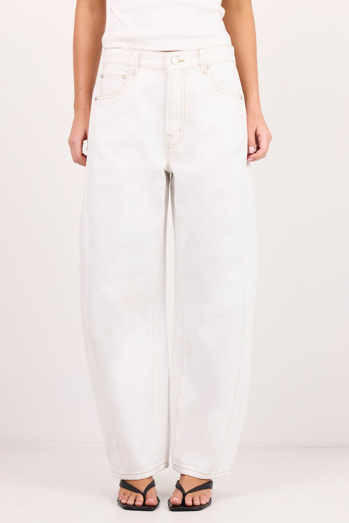 A person wearing white wide-leg jeans with a white top and black sandals, standing against a plain light background.