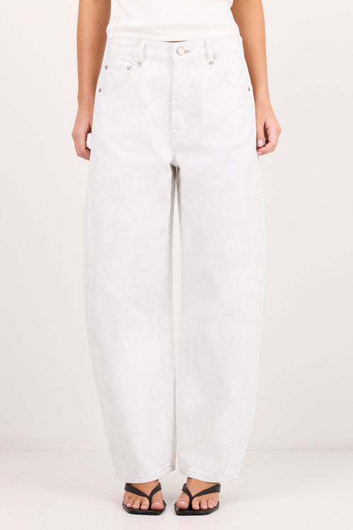 A person wearing white wide-leg jeans with a white top and black sandals, standing against a plain light background.