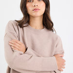 Woman wearing a beige sweater against a white background