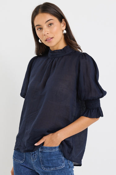 model wears a navy blue blouse with dark blue jeans