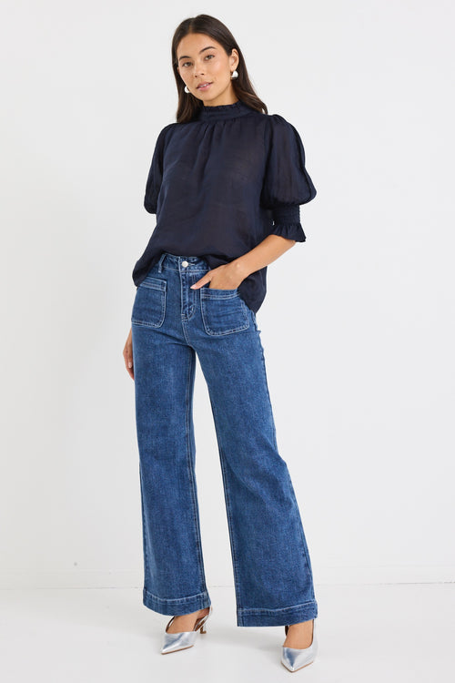 model wears a navy blue blouse with dark blue jeans