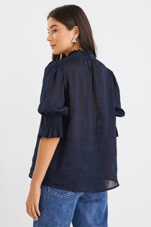 model wears a navy blue blouse with dark blue jeans