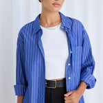 Model wears a blue stripe shirt with black pants