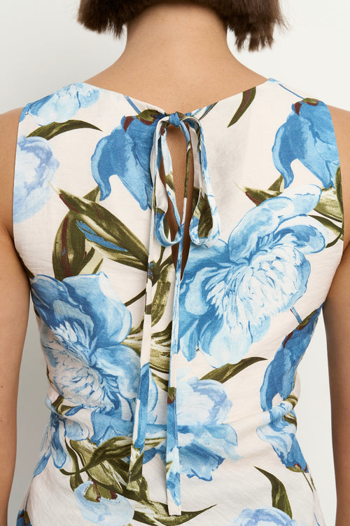 Woman wearing a sleeveless V-neck top with a vintage blue floral print, styled with blue high-waisted jeans.