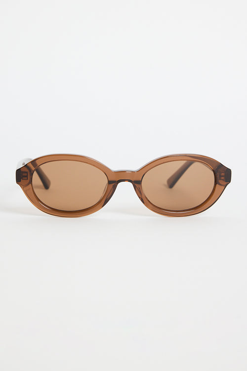 Espresso-brown oval sunglasses with tinted lenses and slim arms featuring RE:UNION label branding, photographed on a white background