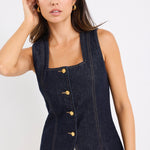 model wears a dark blue denim vest with a beige linen midi skirt