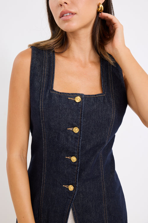 model wears a dark blue denim vest with a beige linen midi skirt