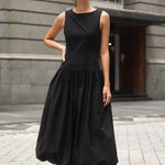 Woman wearing a black bubble hem midi dress, styled with black flats for a playful yet sophisticated look.