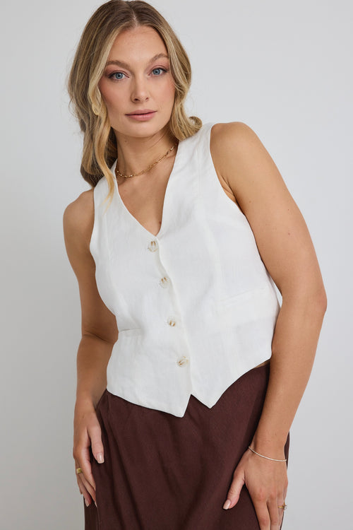 model wears a white vest and a long brown linen skirt