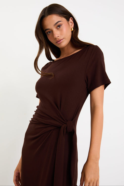 Model wearing a chocolate brown short sleeve jersey maxi dress with a waist tie and side split