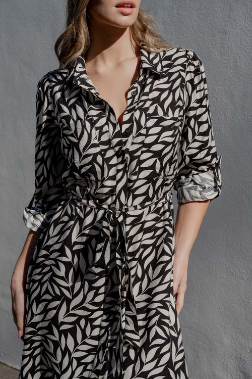 Woman wearing a black and white patterned dress against a gray background