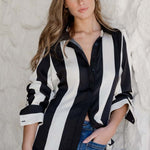 Woman wearing a black and white striped shirt against a textured white wall.