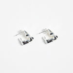 silver-plated brass huggie earrings with a wavy, organic design, photographed flat against a white background.
