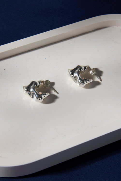 Silver earrings on a white tray with a dark background
