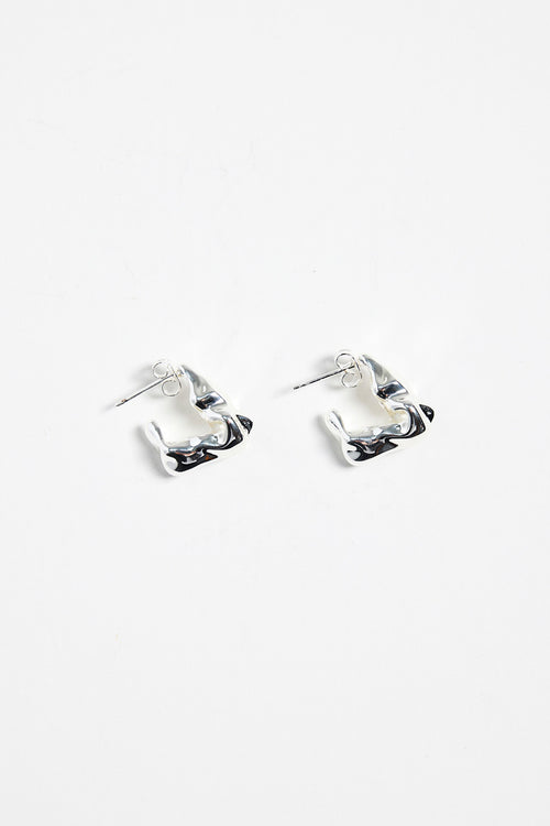 silver-plated brass huggie earrings with a wavy, organic design, photographed flat against a white background.