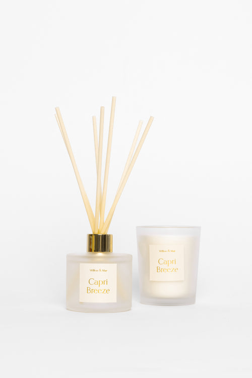 Two diffusers, one with reeds and a candle, on a white background