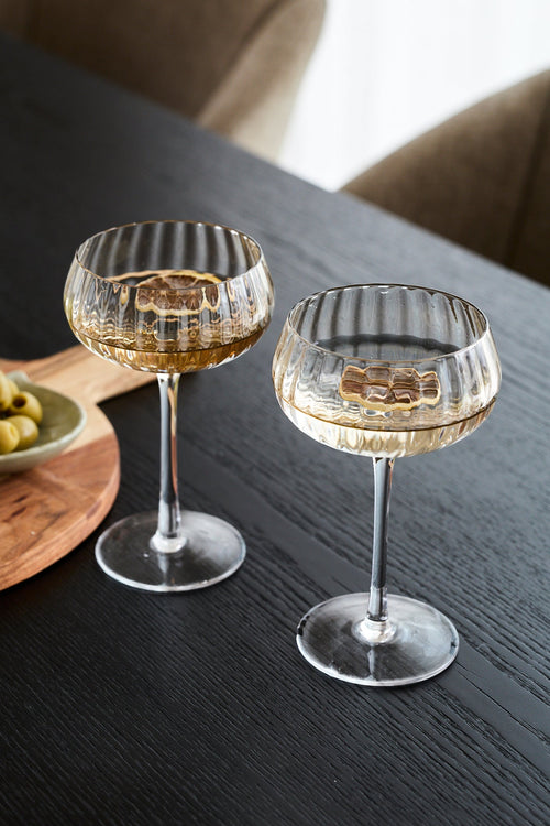 Two clear ribbed-stone wine glasses filled with white wine