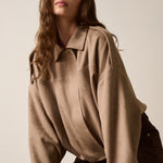 Woman wearing a beige shirt against a plain background