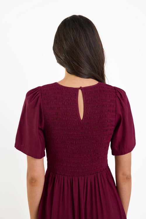 Maroon dress with a cut-out back detail on a white background