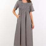 Woman wearing a gray checkered dress on a white background
